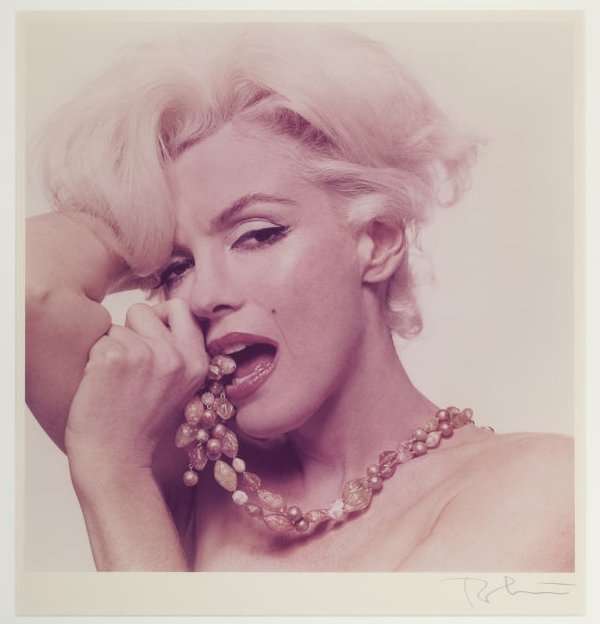 Marilyn Monroe poses as she bites on a necklace semi nude
