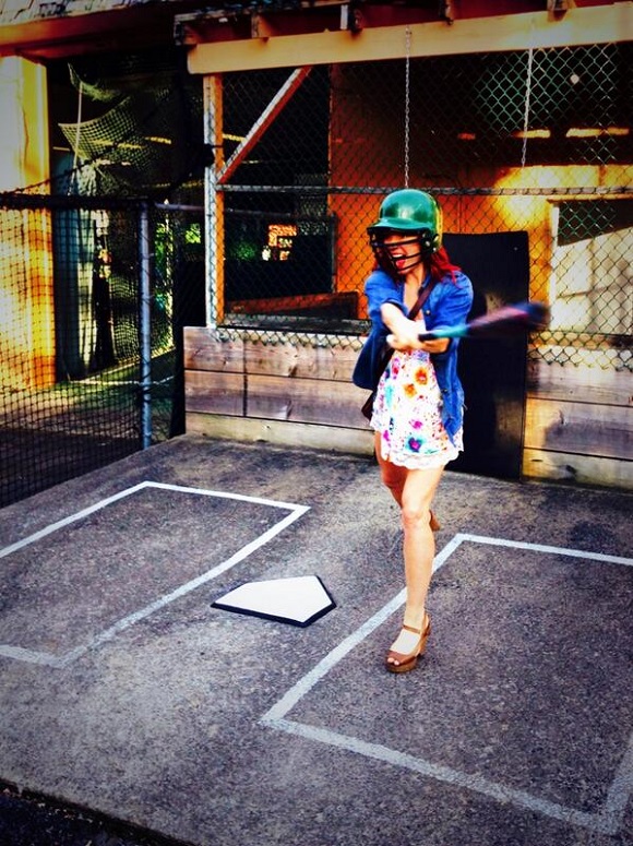 Candy Olsen swings baseball bat in batting cage.