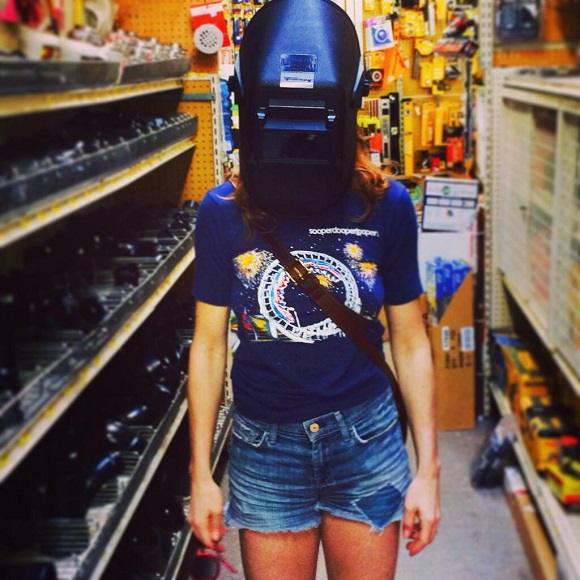 Candy Olsen wears a welding helmet inside a hardware store.